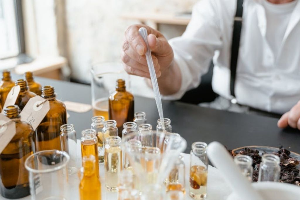 
A perfumer using a pipette to blend fragrance oils in small amber bottles.
