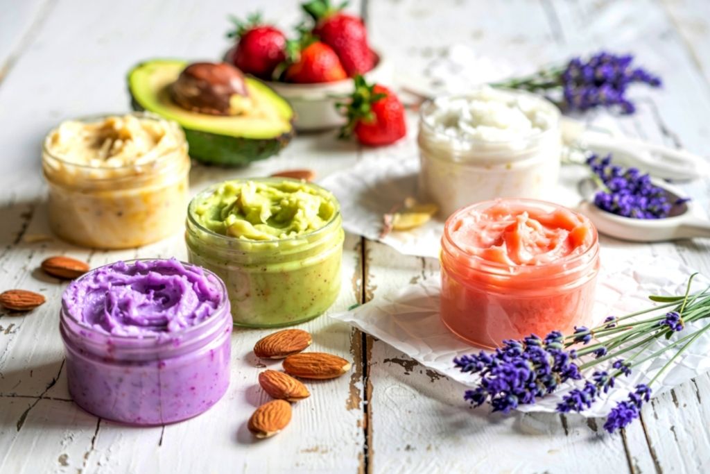Five jars of colorful body butter, symbolizing skincare scented with essential oil (lavender) or fragrance.